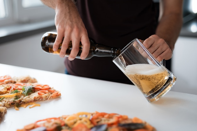 Foto de primer plano de un hombre vierte cerveza en un vaso.