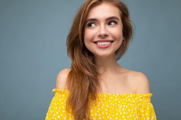 Foto en primer plano de la joven y atractiva mujer rubia sonriente con sinceras emociones aisladas sobre fondo