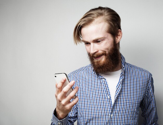 Foto de primer plano de un joven barbudo mirando la pantalla del teléfono inteligente