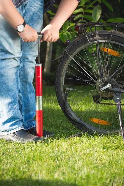 Foto en primer plano del joven rueda de bicicleta de bombeo sobre el césped