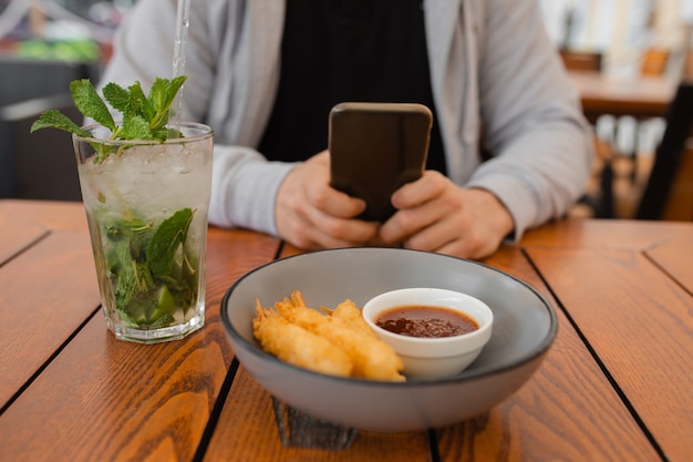 Foto foto de primer plano de las manos del hombre en la mesa de café con teléfono inteligente, concepto de dispositivo móvil