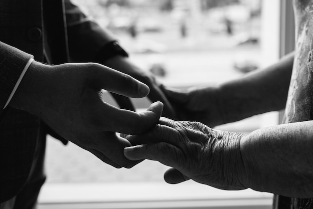 Foto de primer plano de las manos del nieto sosteniendo las manos de la abuela Apoyo de los padres Manos aisladas sobre un fondo blanco Foto en blanco y negro