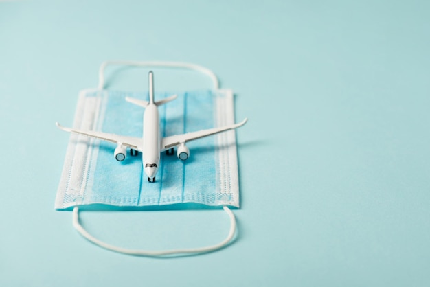 Foto de primer plano del modelo de avión en máscara médica aislado fondo azul con copyspace