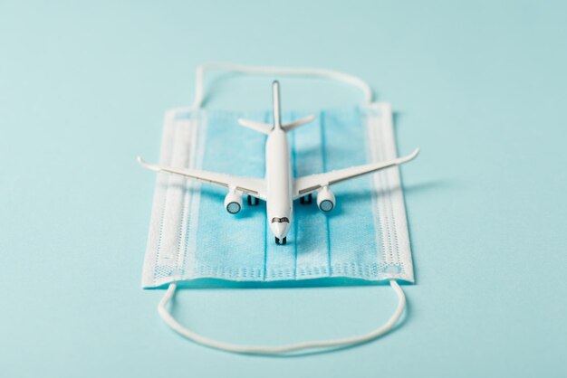 Foto de primer plano del modelo de avión en máscara médica aislado fondo azul con copyspace