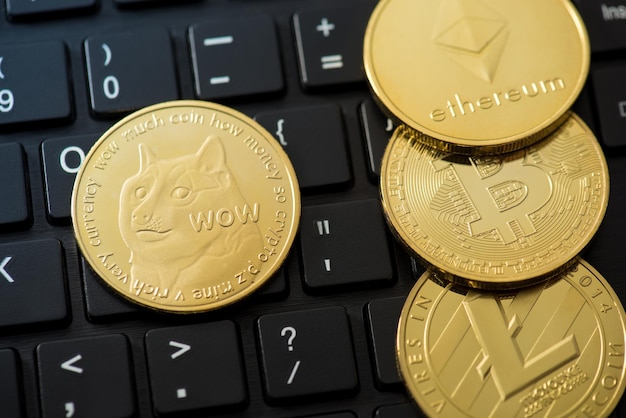 Foto de primer plano de monedas de oro con dogecoin ethereum bitcoin y litecoin símbolos sobre fondo de teclado negro