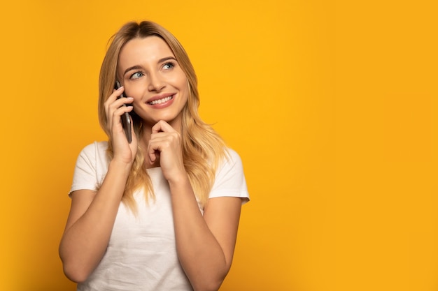 Foto de primer plano de una mujer enigmática, que sonríe mientras mira hacia la esquina superior derecha y habla por teléfono