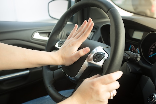 Foto foto en primer plano de mujer molesta conduciendo coche y tocando la bocina