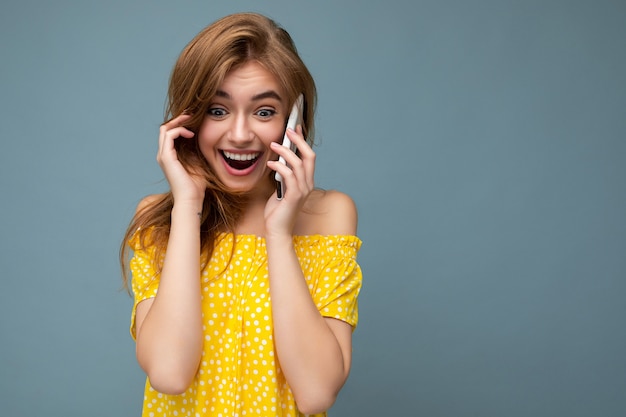 Foto en primer plano de una mujer rubia joven asombrada bastante positiva con un elegante vestido amarillo de verano