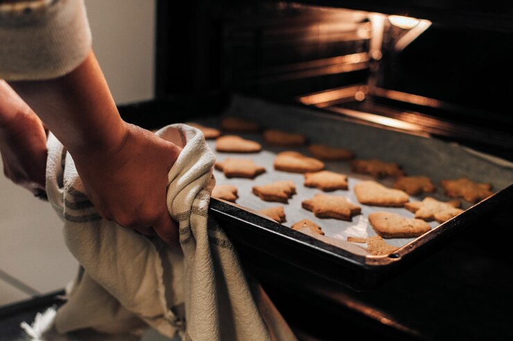 Foto foto en primer plano de una mujer tomando una bandeja de horneado con galletas de navidad del horno