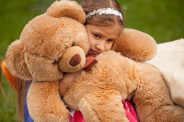 Foto en primer plano de la niña triste abrazando a un oso de peluche