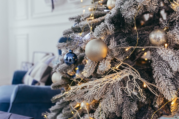 Foto de primer plano de una rama de árbol de Navidad azul decorada con decoración de oro y plata