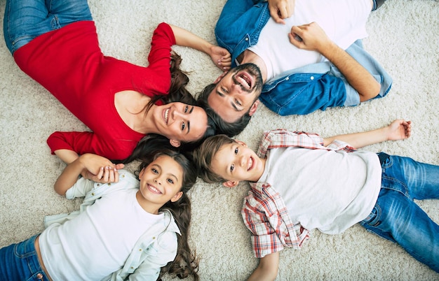 Foto de primera vista de una joven familia feliz tirada en el suelo, diviértete y sonríe