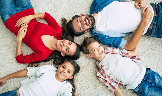 Foto de primera vista de una joven familia feliz tirada en el suelo, diviértete y sonríe