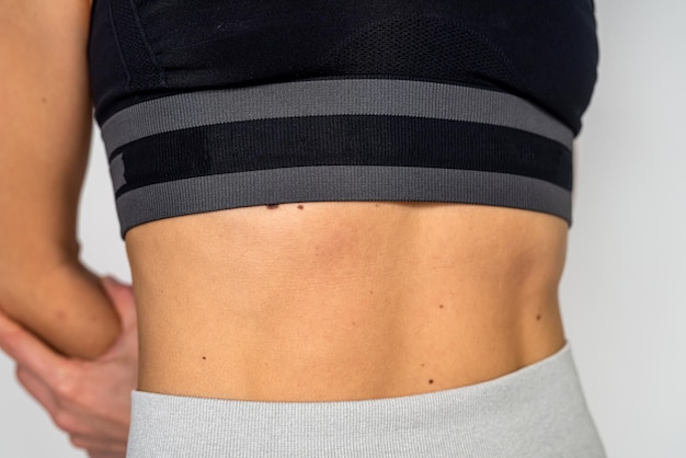 Foto recortada de los abdominales de la mujer después del entrenamiento aislado sobre fondo blanco.