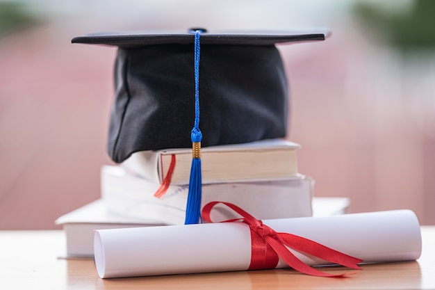 Foto foto recortada de un birrete de sombrero de graduación universitaria y certificado de diploma en la mesa