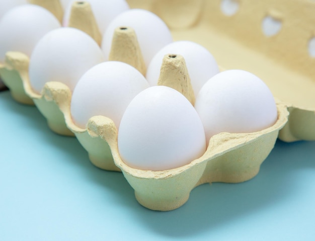 Foto recortada de un cartón de huevos lleno sobre el fondo azul.