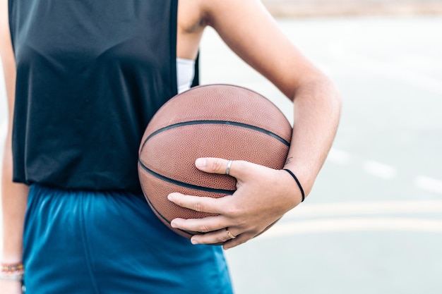 Foto recortada com espaço de cópia de uma mulher segurando uma bola de basquete na mão ao ar livre