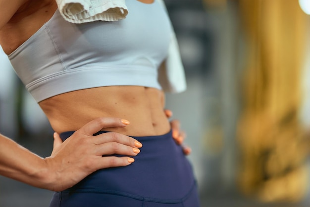 Foto recortada de cuerpo ideal de mujer fitness con abdominales perfectos de pie en el gimnasio el enfoque selectivo