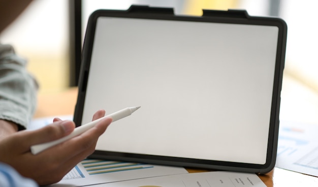 Foto recortada da caneta apontando mão de empresário no tablet digital para apresentar o projeto aos clientes.