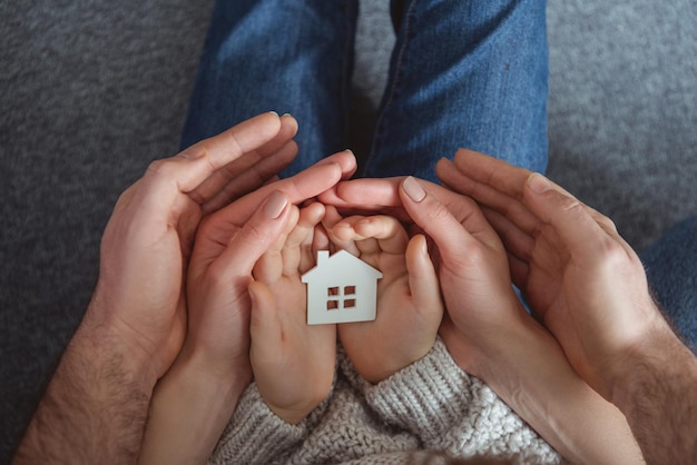 foto recortada da família segurando o modelo de casa pequena nas mãos