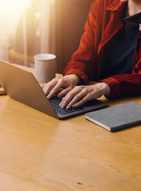 Foto recortada da mulher asiática de negócios freelancer segurando a xícara de café e fazendo o planejamento, analisando o relatório financeiro, plano de negócios, investimento, análise financeira, local de trabalho