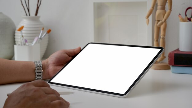 Foto recortada de artista masculino trabalhando no tablet de tela em branco com caneta stylus, ferramentas de pintura e decorações