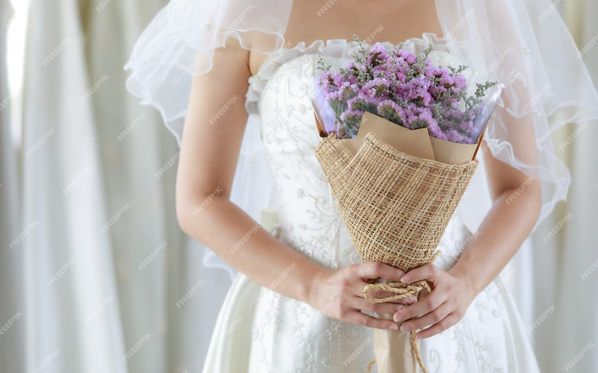 Foto recortada de buquê de flores do casamento roxo, realizada nas mãos da  noiva irreconhecível em um vestido branco com pé de véu de cabelo  seethrough sorrindo olhar para a câmera no