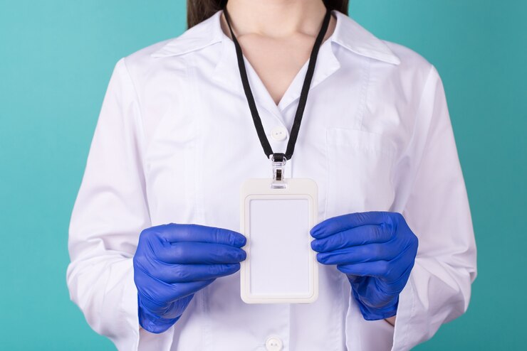 Foto foto recortada de close-up de médica em luvas usando jaleco branco uniforme de risco biológico um crachá em branco vazio simulado isolado no fundo azul esverdeado