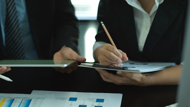 Foto recortada de dois empresários fazendo consultoria sobre o trabalho com gráfico de negócios e tablet