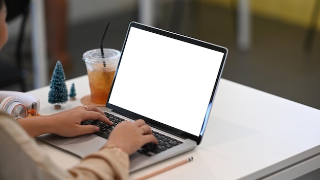 Foto recortada de empresária fazendo transações no laptop na mesa do escritório.