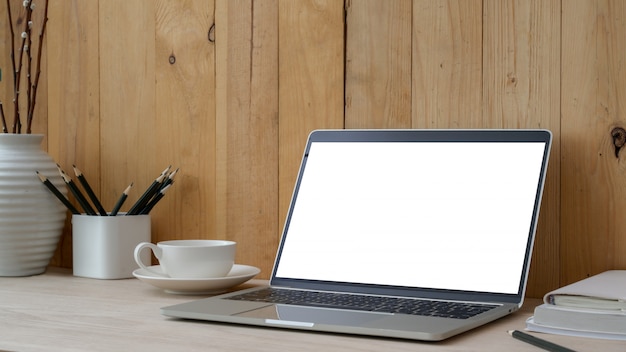 Foto recortada de espaço de trabalho com laptop de tela em branco, material de escritório e decorações