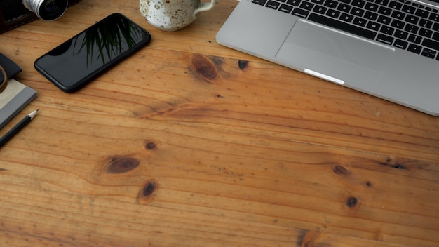 Foto recortada de espaço de trabalho com laptop, xícara de chá, smartphone e cópia espaço na mesa de madeira rústica