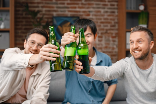 Foto recortada de garrafas de cerveja nas mãos de homens assistindo a um jogo de futebol