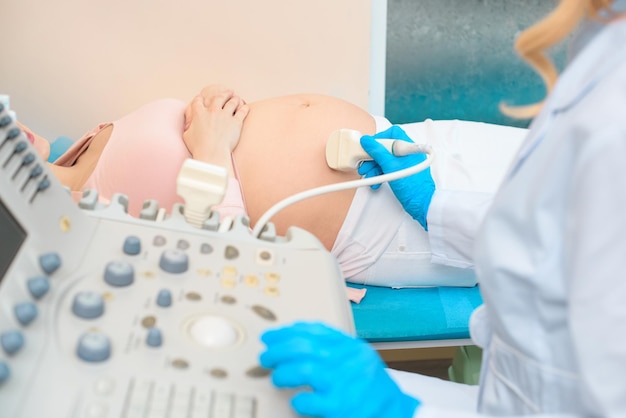 Foto recortada de ginecologista obstetra fazendo ultra-som para mulher grávida