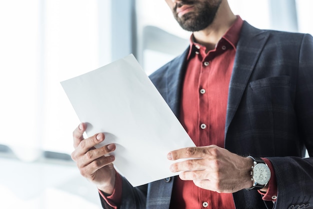 Foto foto recortada de jovem empresário lendo documento de negócios