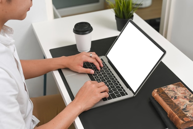 Foto recortada de jovem freelancer navegando na internet no laptop em casa.