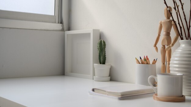 Foto recortada de local de trabalho moderno com laptop de tela em branco, cópia espaço e artigos de papelaria