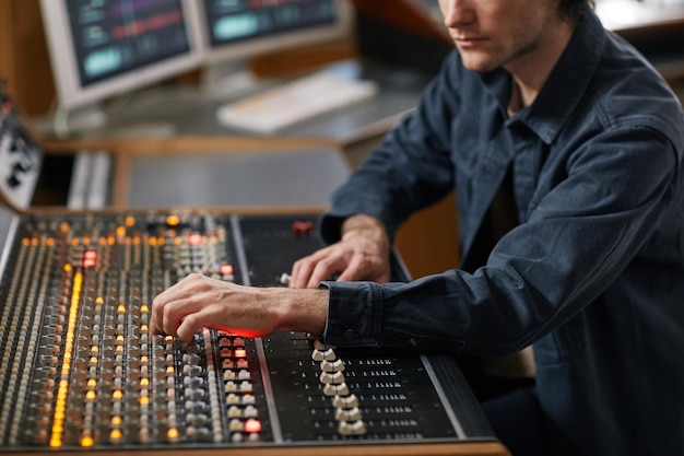 Foto foto recortada de macho de produtor musical usando estação de trabalho de áudio digital em estúdio de gravação profissional