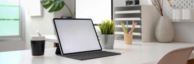 Foto recortada de mesa de escritório portátil com dispositivos de computador, suprimentos e decorações