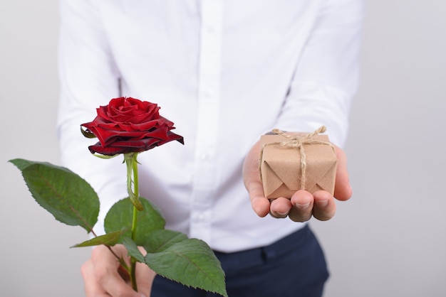 Foto recortada de perto, retrato de um homem bonito charmoso feliz alegre positivo segurando um pequeno presente e um fundo cinza rosa brilhante