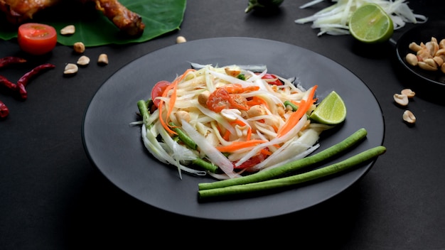 Foto recortada de salada de papaia, grelha de frango e ingredientes na chapa preta