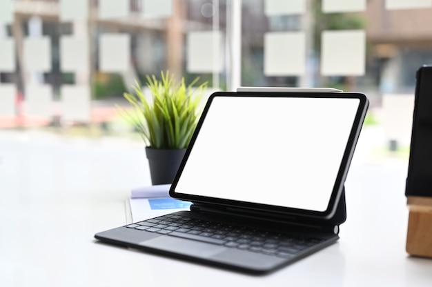 Foto recortada de tablet com teclado inteligente na mesa branca. Tela em branco para montagem de display gráfico.