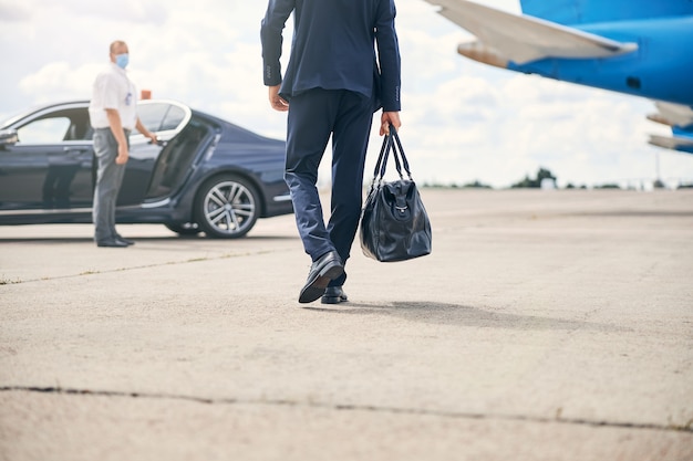 Foto recortada de um empresário de sucesso carregando uma mochila indo em direção a um táxi