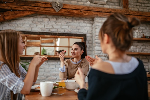 Foto recortada de um grupo de amigas tomando café da manhã na cozinha