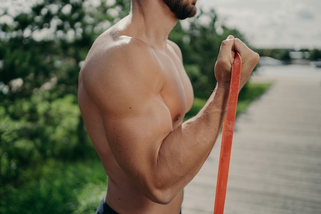 Foto recortada de um homem musculoso irreconhecível mostrando exercícios de bíceps de treino de perfil mostrando músculos fortes