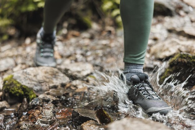 Foto recortada de uma caminhante de mulher irreconhecível atravessando um riacho enquanto explorava a floresta.