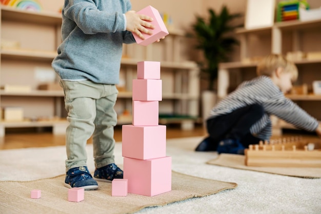 Foto recortada de uma criança construindo uma torre com blocos de madeira e jogando jogos com brinquedos