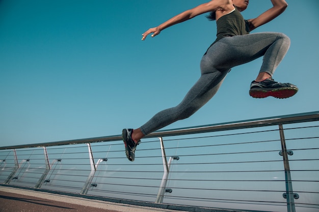 Foto recortada de uma desportista em movimento ao lado do corrimão ao ar livre. Banner do site