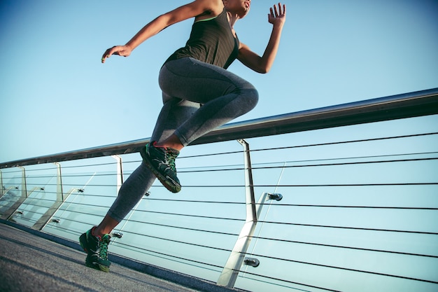 Foto recortada de uma esportista se exercitando na ponte e colocando um joelho para cima