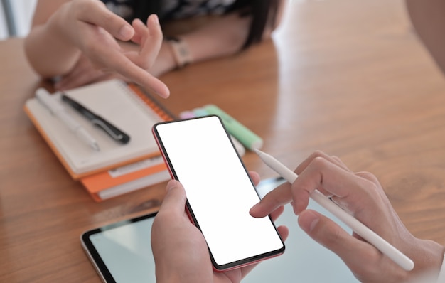 Foto recortada de uma jovem mulher apontando um smartphone na mão da amiga